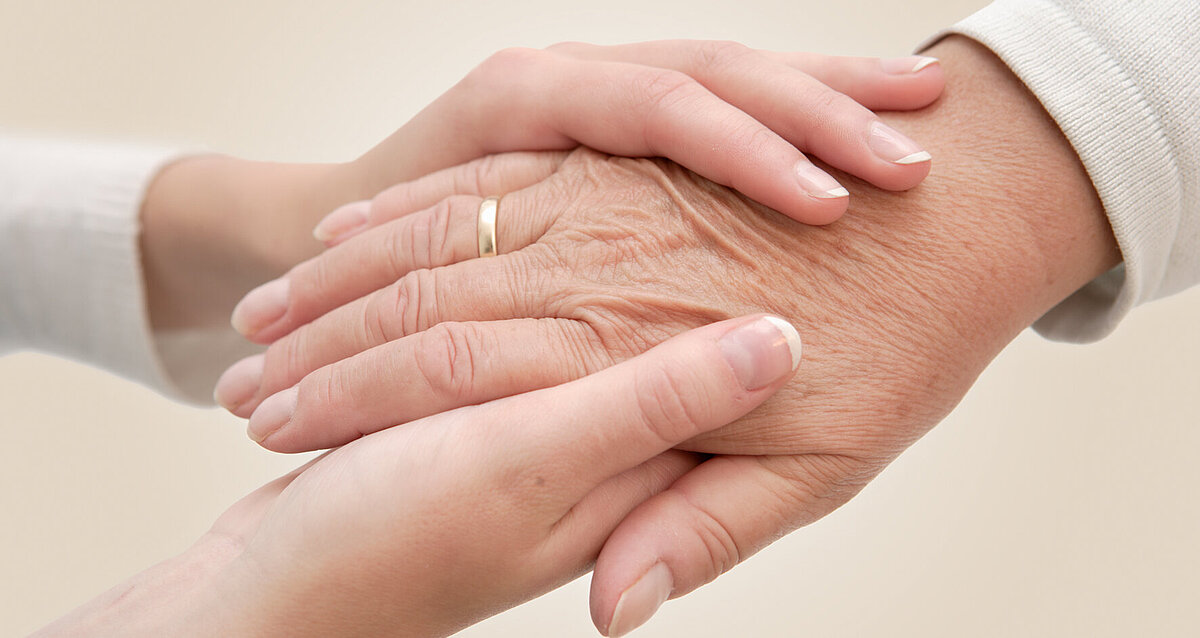 Bild von zwei jüngeren Händen, die eine ältere Hand halten.