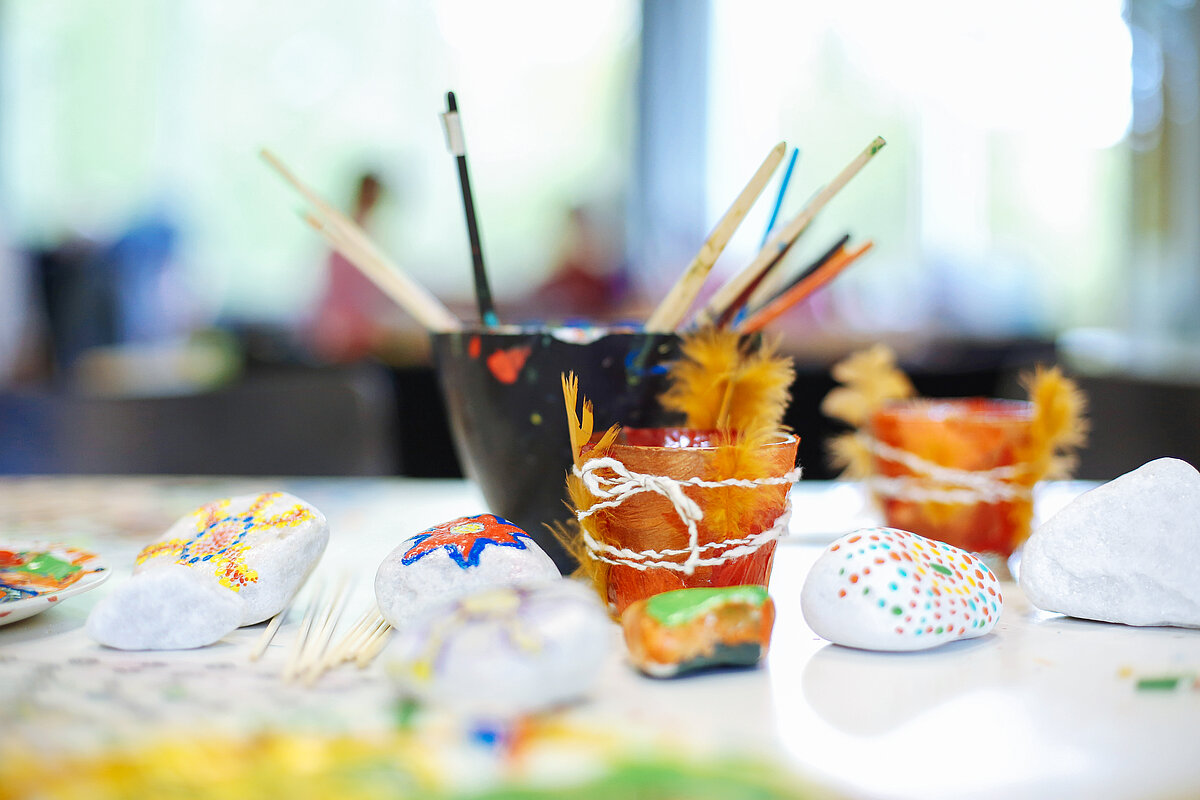 Bemalte Steine und ein Becher mit Pinseln