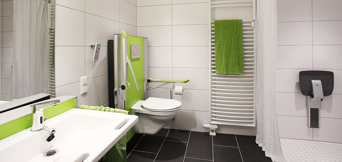 Badezimmer mit höhenverstellbarem WC und anderen Hilfsmitteln